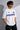 Man wearing a white BMW oversized t-shirt with blue, light blue, and red stripes across the chest and a black Puma logo and BMW M Motorsport emblem.