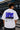 Model wearing white POPCASE Carlos Sainz Williams Racing oversized t shirt with blue W logo at Formula 1 circuit pitlane