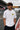Model wearing white POPCASE Charles Leclerc Scuderia Ferrari oversized t shirt with prancing horse shield badge at F1 circuit pitlane
