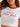 Woman in white ringer crop top with red trim and 'New York' graphic, paired with denim shorts, sitting on a couch.