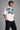 Model wearing a white DIMENSION oversized t-shirt with a black and blue graphic print and a silver chain necklace.