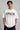 Man wearing a white oversized FAKR t-shirt with a graphic design of the word "Fakr" integrated with superhero symbols, on a plain gray background.