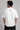 Man wearing a white oversized FAKR t-shirt with a graphic design of the word "Fakr" integrated with superhero symbols, on a plain gray background.