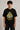 Black oversized t-shirt with the Hogwarts crest and 'Hogwarts' text in yellow, worn by a person. Features detailed coat of arms with lions, snakes, badgers, and eagles.