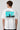 Model wearing white POPCASE Kimi Antonelli Mercedes oversized t shirt with teal MERCEDES Petronas F1 car back graphic and bio text