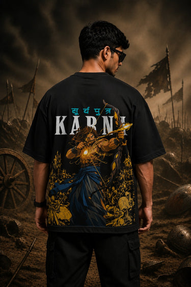 Man wearing a black KARNA oversized t-shirt with a sun graphic and Sanskrit text. Streetwear style, premium cotton feel. - black