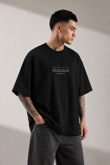 Black POPCASE LAUNCH oversized t-shirt featuring a large, distressed gray wing graphic print. Close-up on the premium fabric and detailed print for a streetwear aesthetic.