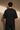 Back view of a person wearing a black ART ON OVERSIZED TSHIRT with gold embroidered detail on the left sleeve. Shows the oversized fit and premium streetwear aesthetic.