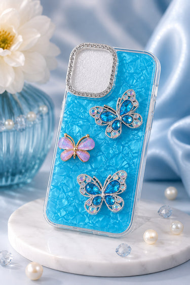 Blue phone case with butterfly designs on a marble surface with flowers and pearls.