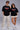 Black POPCASE oversized unisex tshirt with Conquer Yourself in layered red gothic and grey shadow text on front, styled with beige bubble shorts