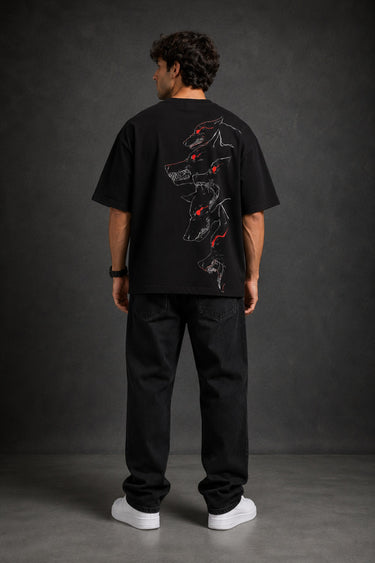 Man wearing a black DISCIPLINE WILD WOLF oversized t-shirt with white 'DISCIPLINE' text, dark wash jeans, and white sneakers, sitting on stairs.
