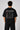 Model wearing a black oversized t-shirt with a small, embroidered Formula 1® logo in white, red, and gray on the chest. Casual streetwear style. - black