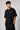 Model wearing a black oversized t-shirt with a small, embroidered Formula 1® logo in white, red, and gray on the chest. Casual streetwear style.