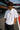 Person wearing a white t-shirt with 'POPCASE' branding on a race track with F1 branding in the background.