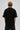Model wearing a black Fast Feels Forever oversized t-shirt with graphic prints, sitting on a leather couch.