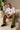 Man wearing a white oversized Real Madrid t-shirt with a circular club crest logo, paired with olive green pants and black sneakers, posing casually with hands in pockets.