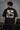 Man wearing FROM THE NORTH oversized t-shirt in beige with black cargo pants and white sneakers. Features The North Face logo and graphic on front and back.