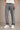 Person wearing gray jeans and white sneakers on a beige background