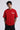 Red oversized t-shirt with 'PROJECTOR HANUMANJI' graphic design of a warrior monkey god and 'POPCASE' logo, worn by a man.