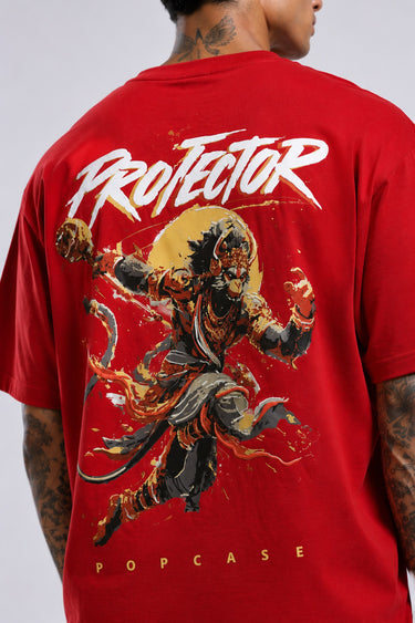 Red oversized t-shirt with 'PROJECTOR HANUMANJI' graphic design of a warrior monkey god and 'POPCASE' logo, worn by a man.