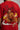 Man wearing a red PROJECTOR HANUMANJI oversized t-shirt with black pants and white sneakers, sitting on metal stairs. - red