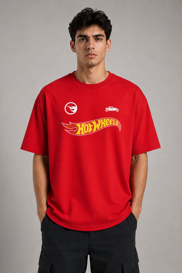 Couple wearing matching red oversized Hot Wheels t-shirts and black bottoms, standing on stairs. Feature iconic Hot Wheels logo. - red