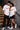 Couple wearing matching red oversized Hot Wheels t-shirts and black bottoms, standing on stairs. Feature iconic Hot Wheels logo. - white