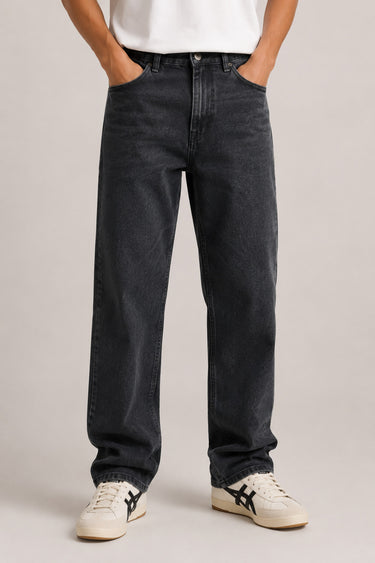Person wearing black jeans and white sneakers on a plain background