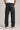 Person wearing black jeans with visible branding on a plain background