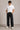 Person wearing a white t-shirt, black jeans, and sunglasses against a plain background