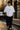 Person wearing a white t-shirt and black pants on a city street.