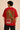 Red oversized t-shirt with "RESILIENCE" embroidered in gold and a green embroidered crocodile graphic. Features a ribbed neckline and premium stitching.
