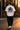Person wearing a white t-shirt with Porsche 911 design walking on a street at sunset.