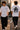 Person wearing a white t-shirt with '911' design, walking on a street.