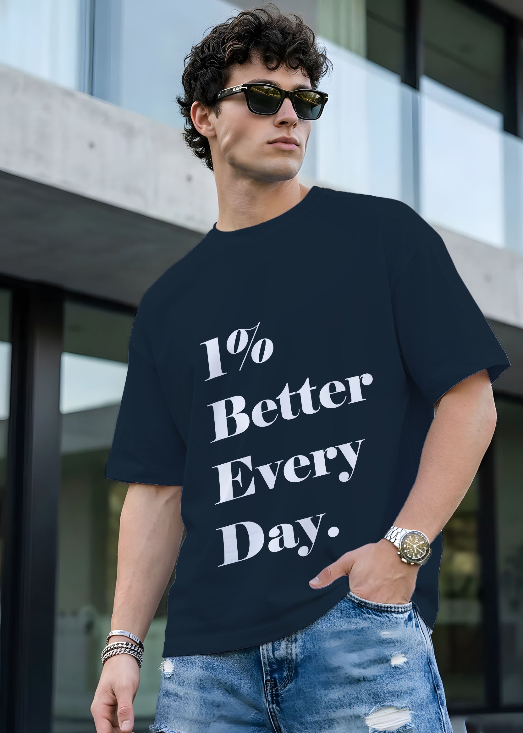 Man wearing a black t-shirt with '1% Better Every Day' text, standing outdoors.