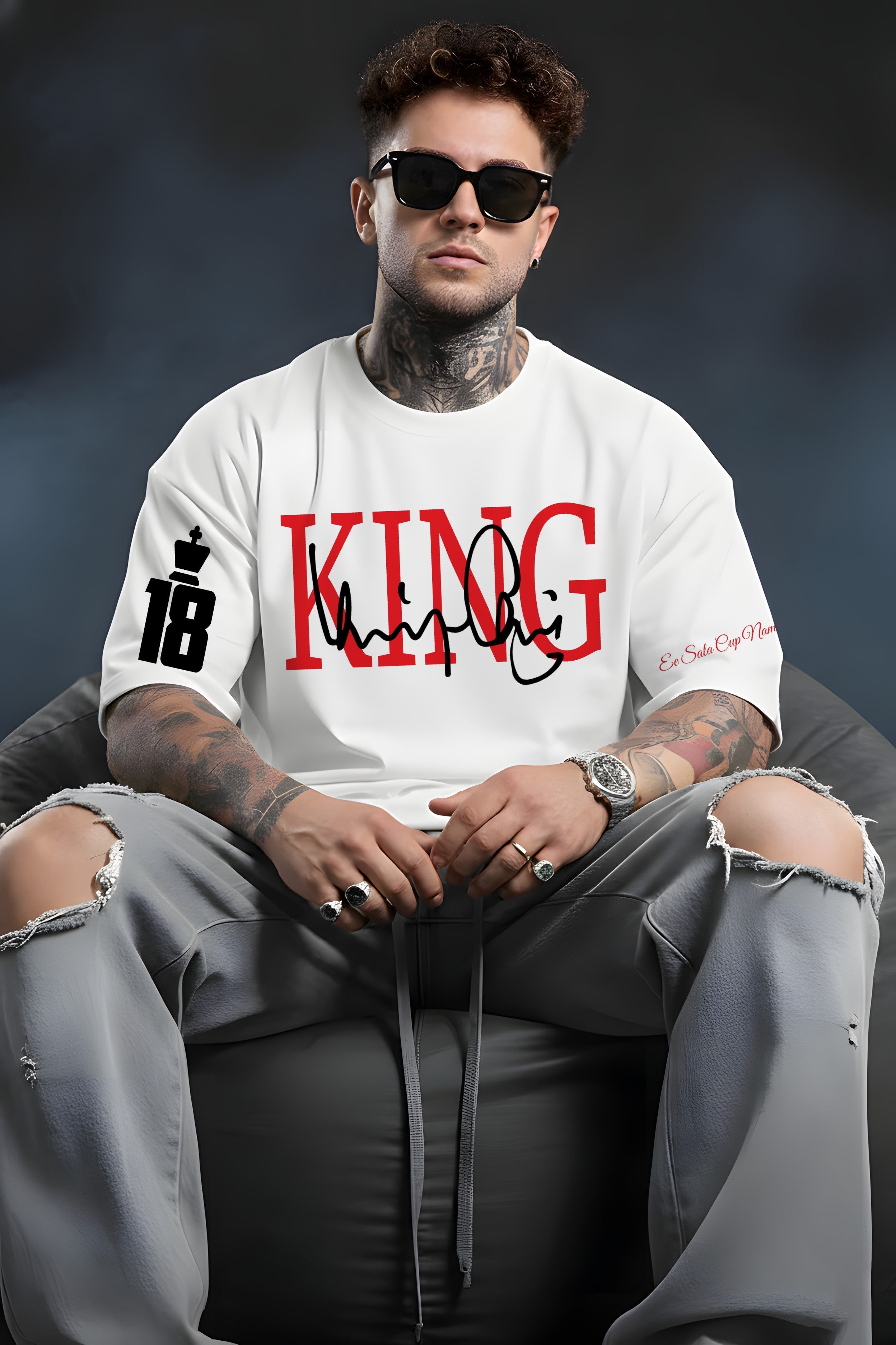 Man wearing a Virat King white t-shirt with 'KING' printed on it, sitting against a dark background.