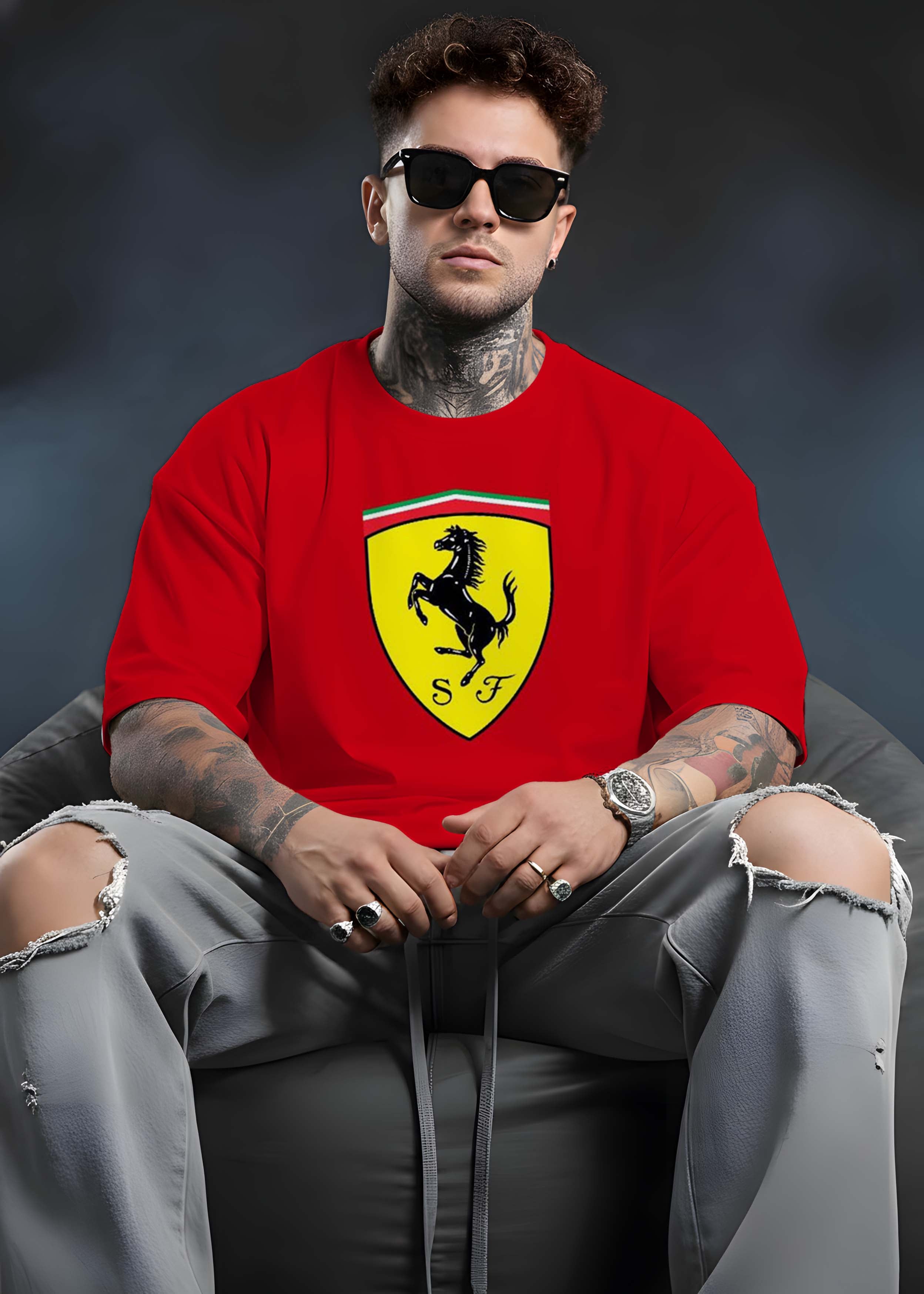 Person wearing a red shirt with a yellow logo sitting on a dark chair.