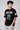 Man wearing a black t-shirt with 'New York 23' and 'Brooklyn' text on a gray background