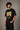 Back view of a man wearing an ENFIELD DESIGN black oversized t-shirt against a textured grey background. Features relaxed fit and premium cotton. - 7