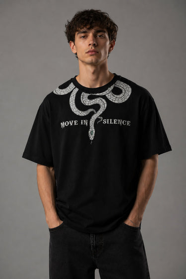 Beige oversized t-shirt with a detailed vintage-style grey snake graphic and 'MOVE IN SILENCE' text. The fabric is soft-washed premium cotton.