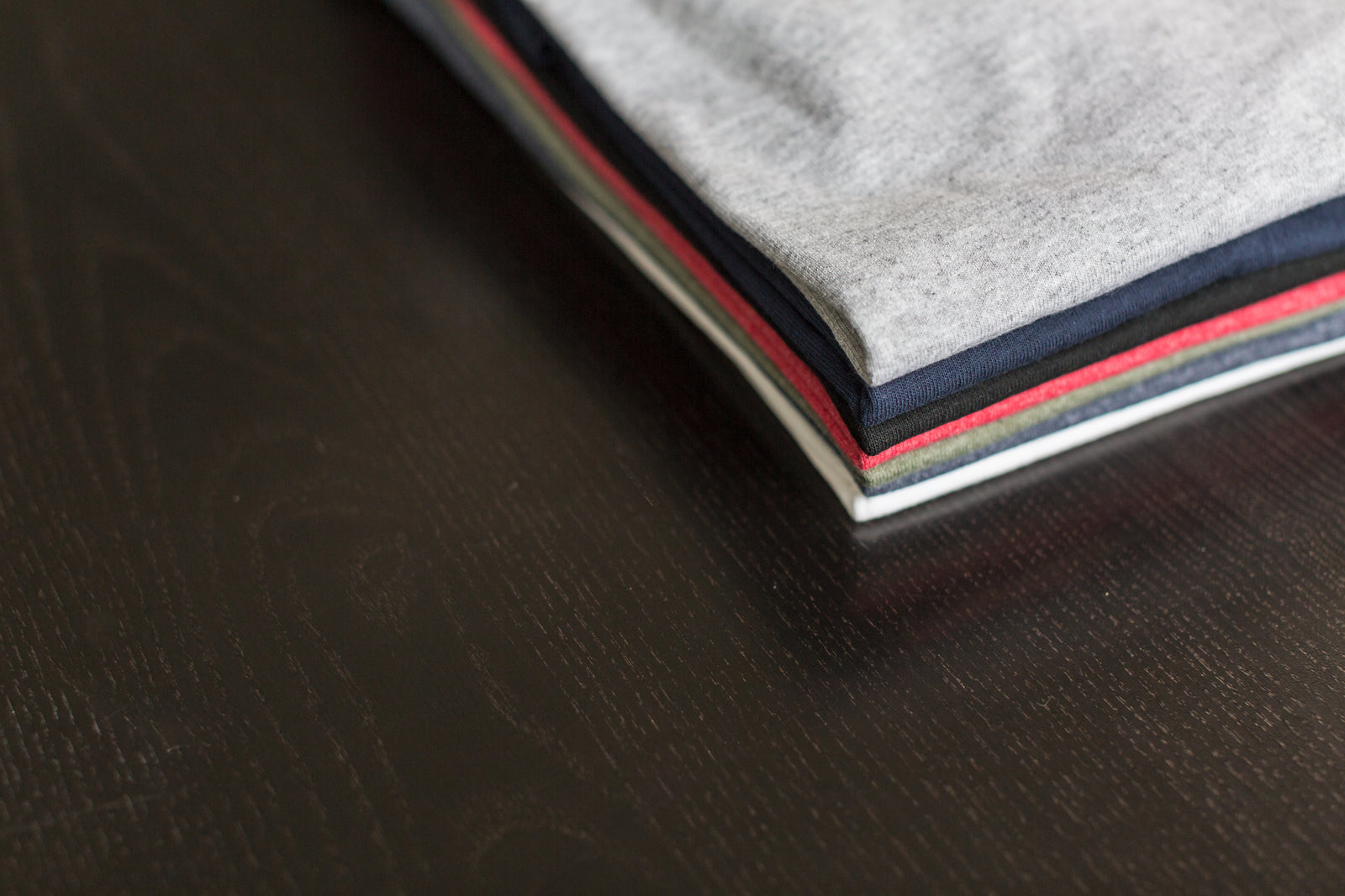 Stack of folded plain oversized t-shirts on a table, showing fabric weight and structure