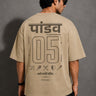 Model wearing a beige POPCASE 5 Pandav oversized t-shirt featuring a large graphic of 'Pandav' in Hindi, '05', and warrior icons. Premium streetwear. - beige