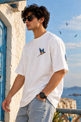 White oversized tshirt with vibrant macaw parrot bird illustration in blue yellow and green on left chest, drop shoulder boxy fit, men India