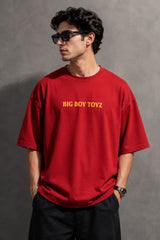 Red BIG BOY TOYZ x Hot Wheels oversized t-shirt featuring a vintage red Hot Wheels car graphic, checkered flag pattern, and brand logos. Showcase print quality and fabric.