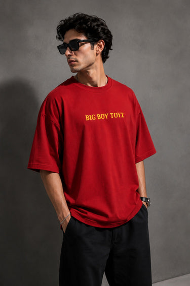 Red BIG BOY TOYZ x Hot Wheels oversized t-shirt featuring a vintage red Hot Wheels car graphic, checkered flag pattern, and brand logos. Showcase print quality and fabric.