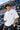 Model wearing white POPCASE Carlos Sainz Williams Racing oversized t shirt with blue W logo at Formula 1 circuit pitlane