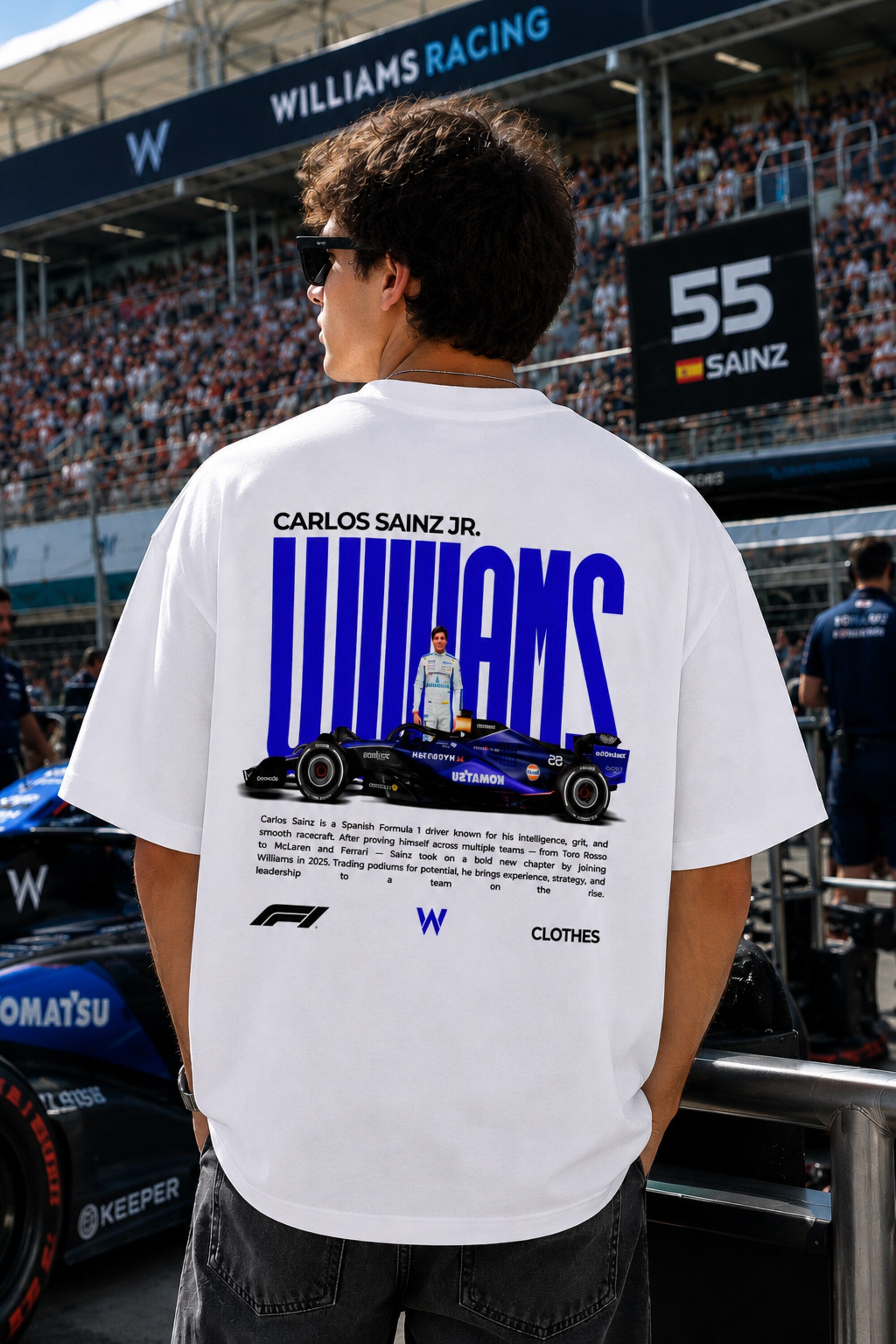 Model wearing white POPCASE Carlos Sainz Williams Racing oversized t shirt with blue W logo at Formula 1 circuit pitlane