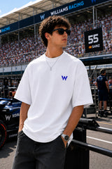 Model wearing white POPCASE Carlos Sainz Williams Racing oversized t shirt with blue W logo at Formula 1 circuit pitlane