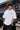 Model wearing white POPCASE Carlos Sainz Williams Racing oversized t shirt with blue W logo at Formula 1 circuit pitlane