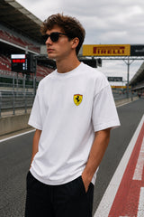 Model wearing white POPCASE Charles Leclerc Scuderia Ferrari oversized t shirt with prancing horse shield badge at F1 circuit pitlane